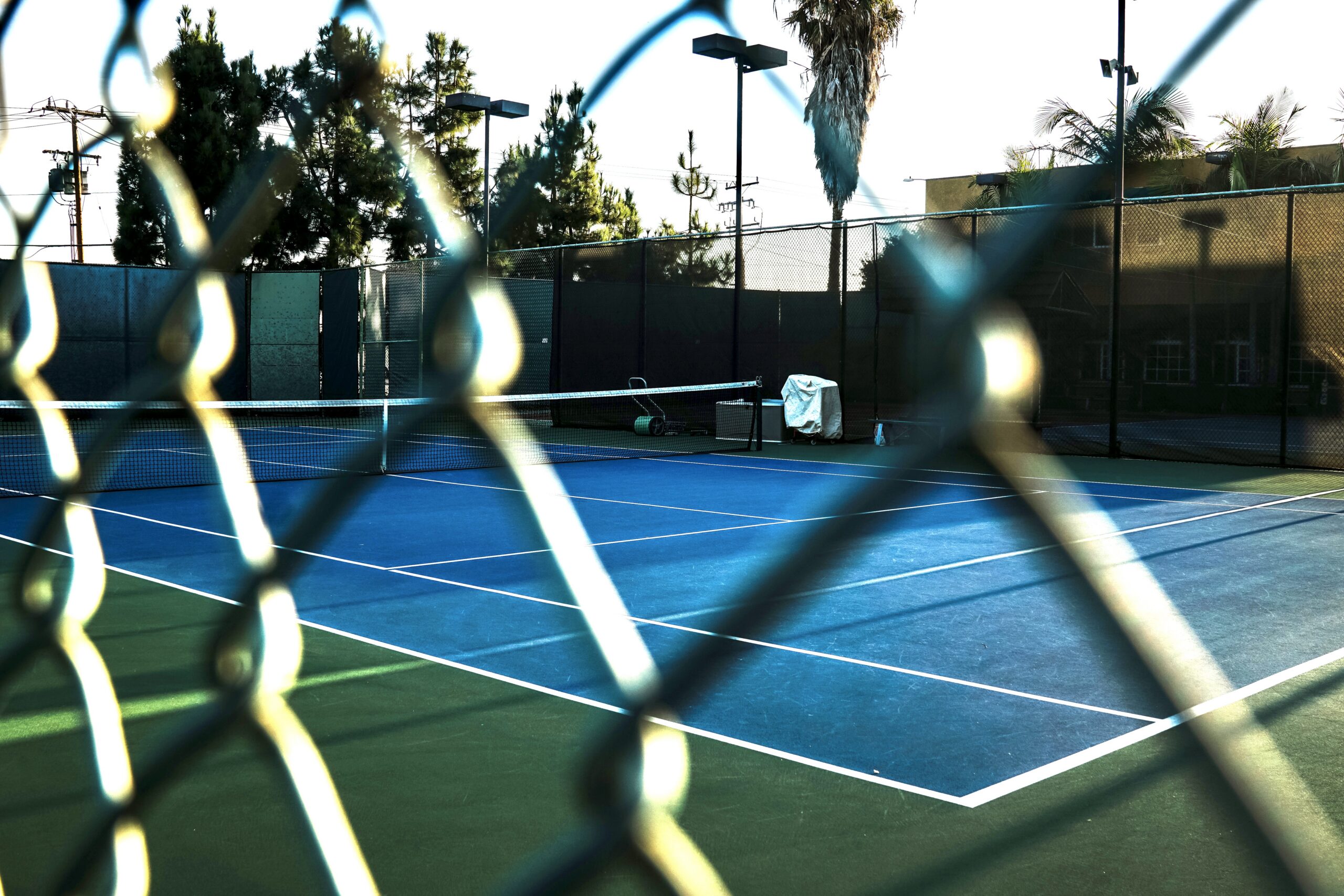 A South End tennis court seen through the fence in late-afternoon sun