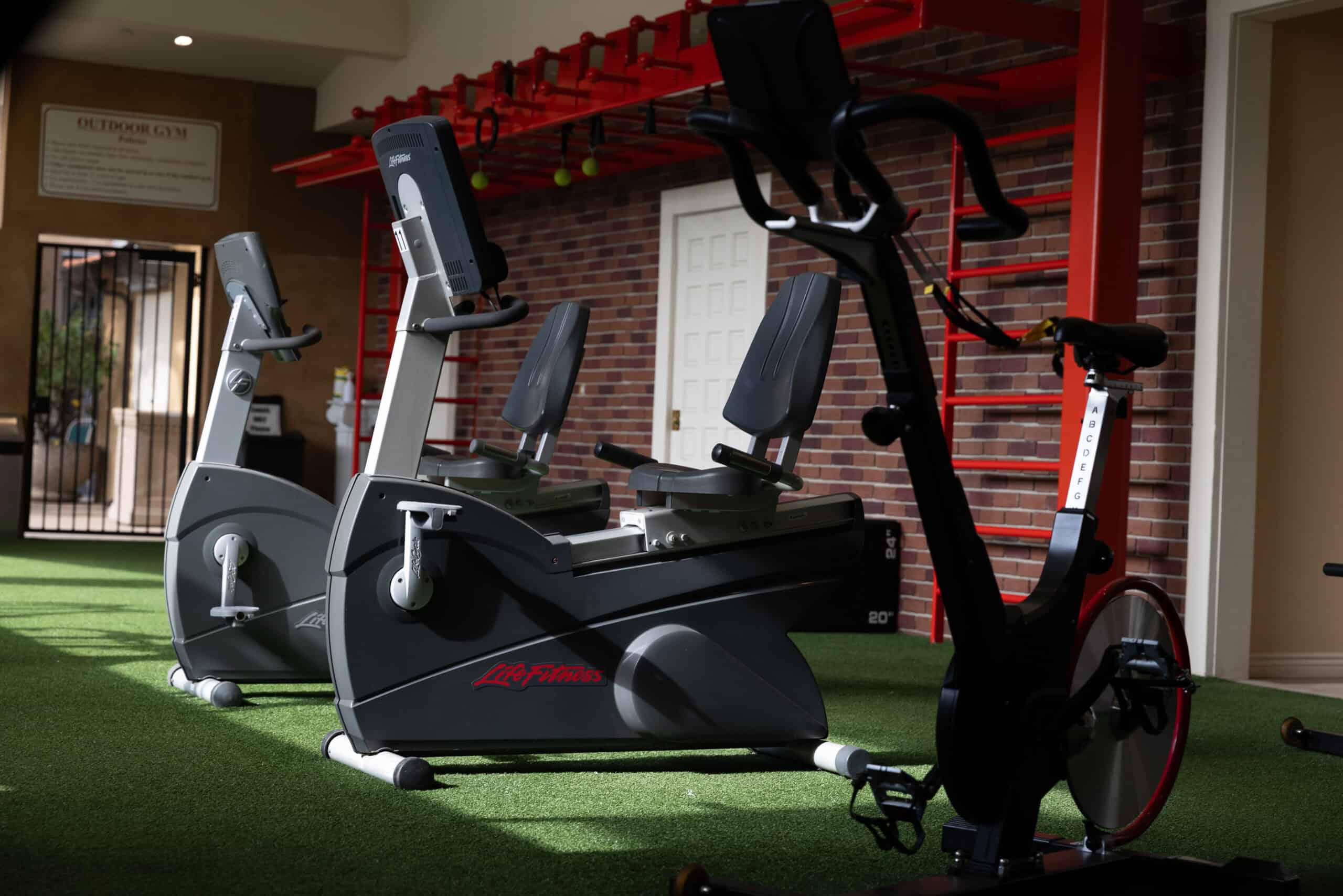 Outdoor gym — cardio bikes and training rig by the brick wall