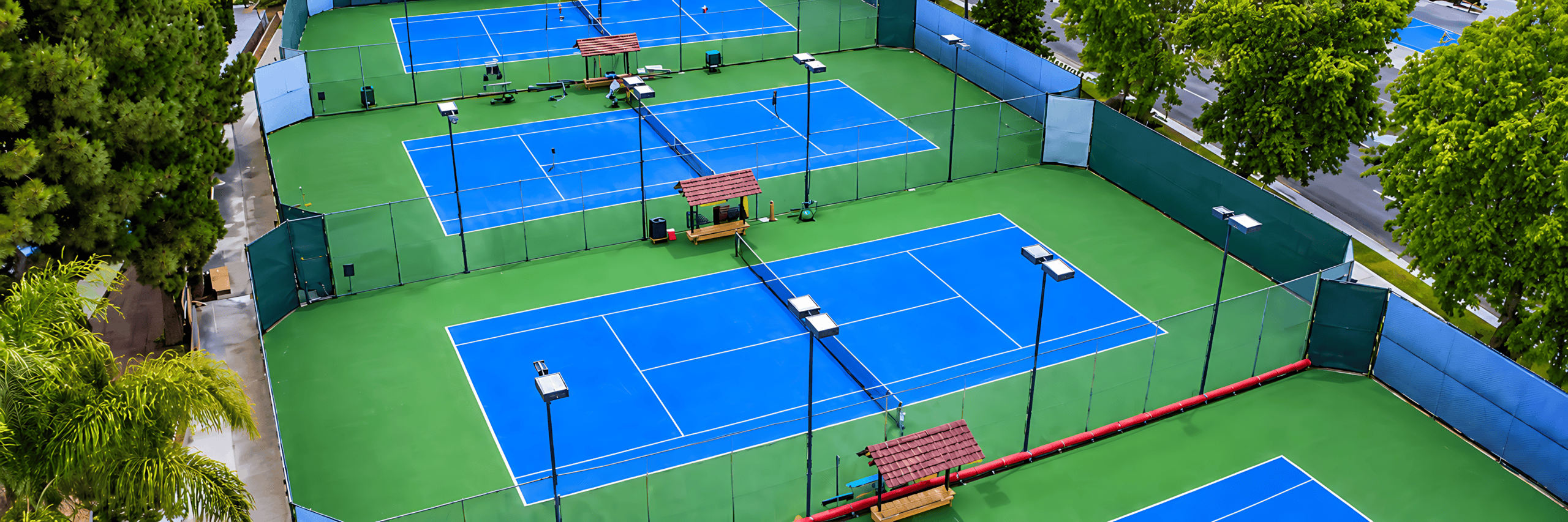 Aerial view of South End's blue tennis courts with palms and wind screens